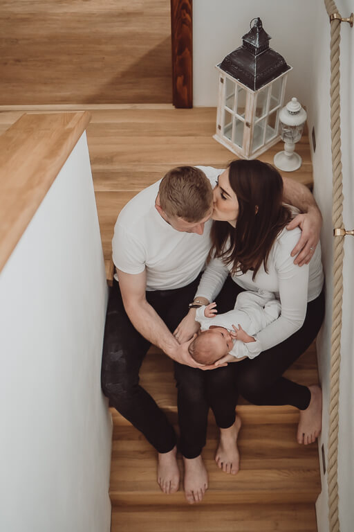 Dokumentární novorozenecké rodinné focení. Maminka s tatínkem sedí na schodech a v rukách drží čerstvě narozeného syna.